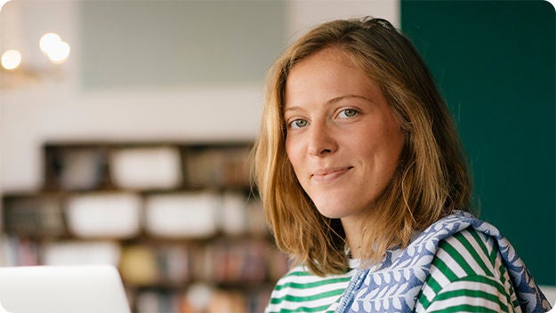 Zwei Personen sitzen an einem Schreibtisch, eine Person lächelt die andere an.
